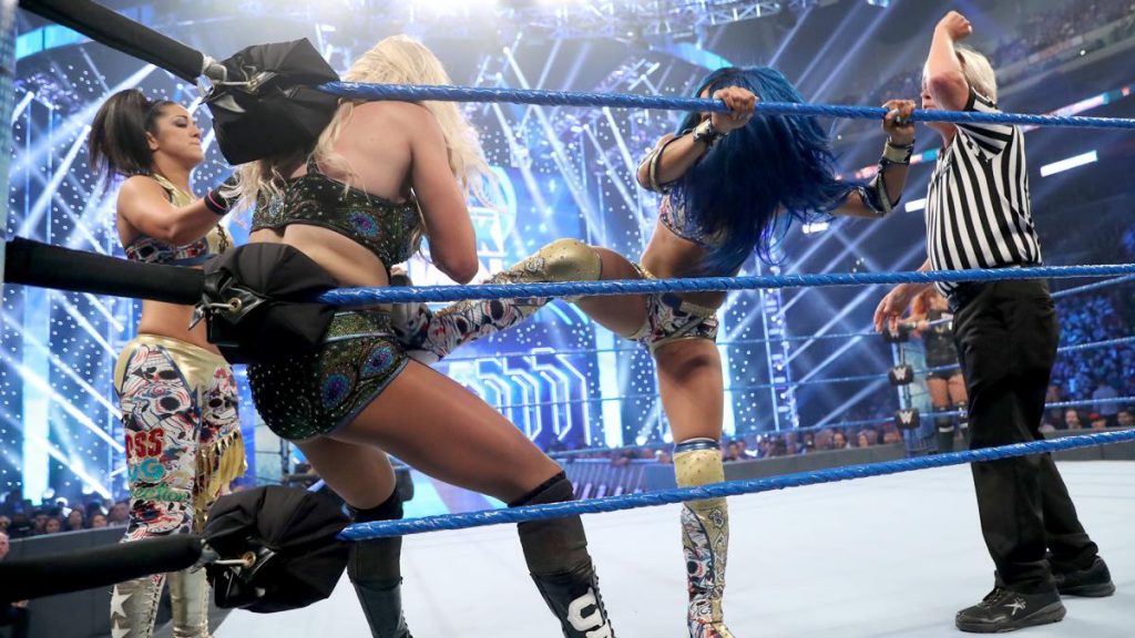 Sasha Banks and Bayley with Charlotte Flair trapped in their corner