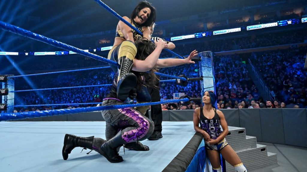 Sasha Banks watches Bayley force Nikki Cross into the ropes