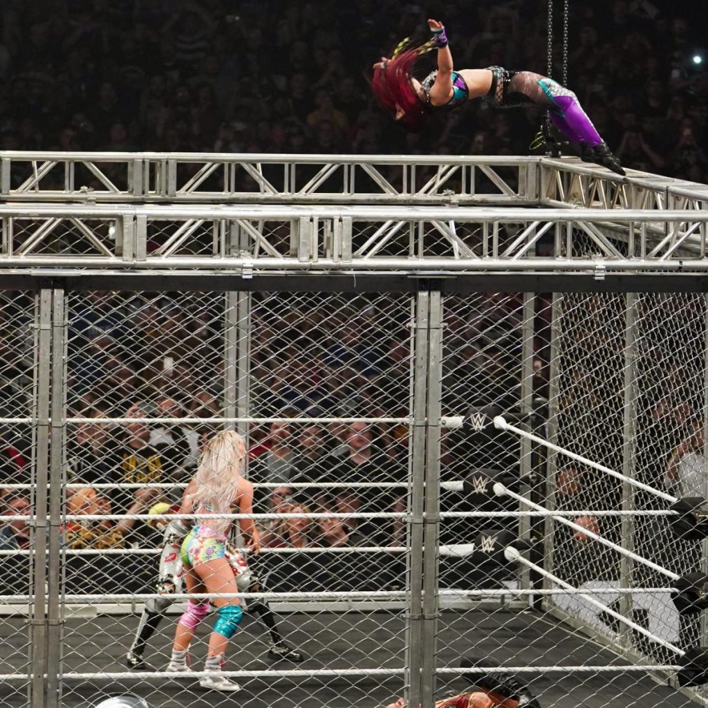 Io Shirai moonsaults off the top of the cage onto Bianca Belair and Candice LeRae