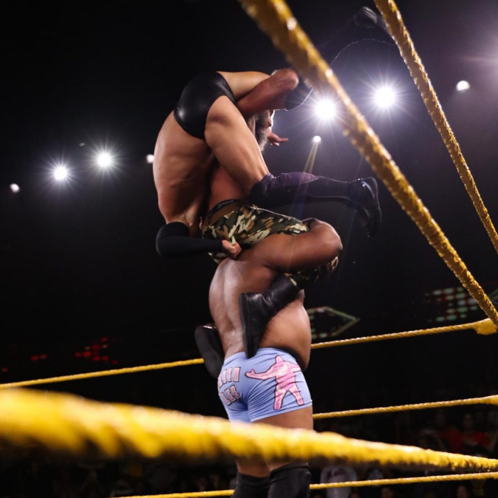 Tommaso Ciampa on Keith Lee's shoulders while holding Balor on his back