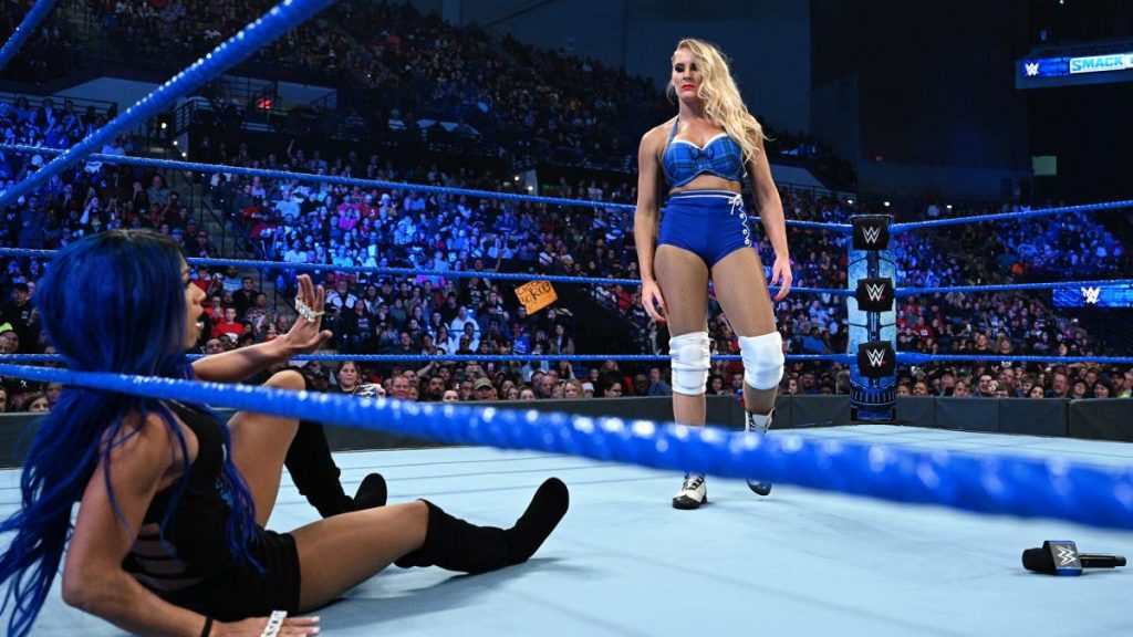 Lacey Evans stands over Sasha Banks sat on the mat