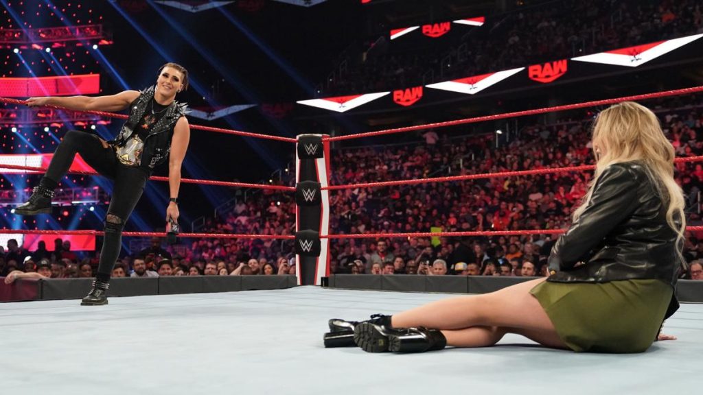 Rhea Ripley smiles at Charlotte Flair after knocking her on her ass
