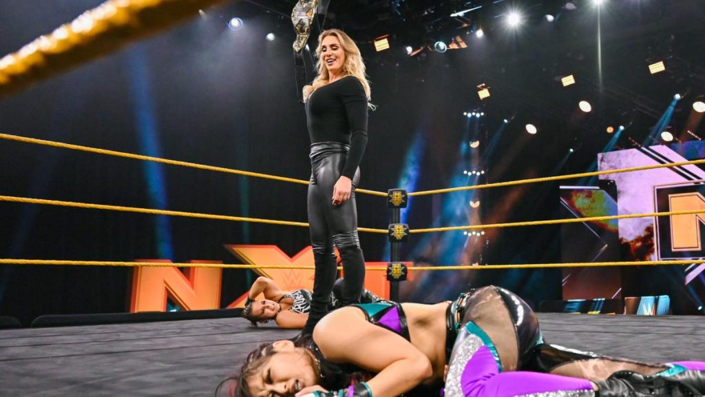 Charlotte Flair stands over Io Shirai and Rhea Ripley