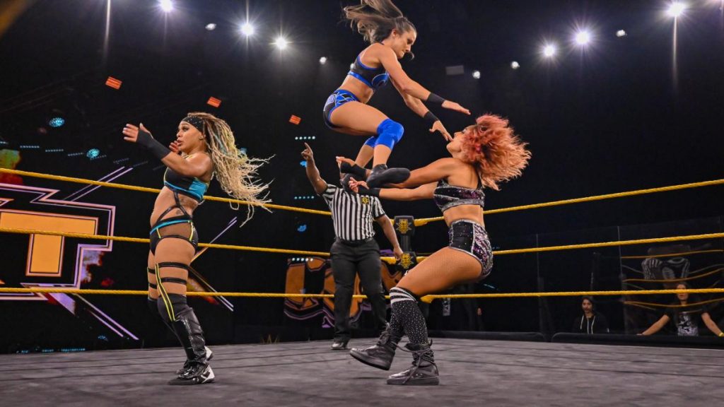 Kacy Catanzaro leaps onto Dakota Kai having been assisted by Kayden Carter