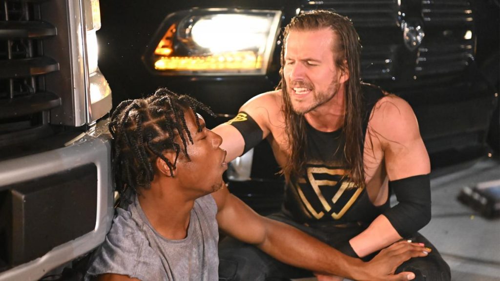 Adam Cole crouches next to Velveteen Dream
