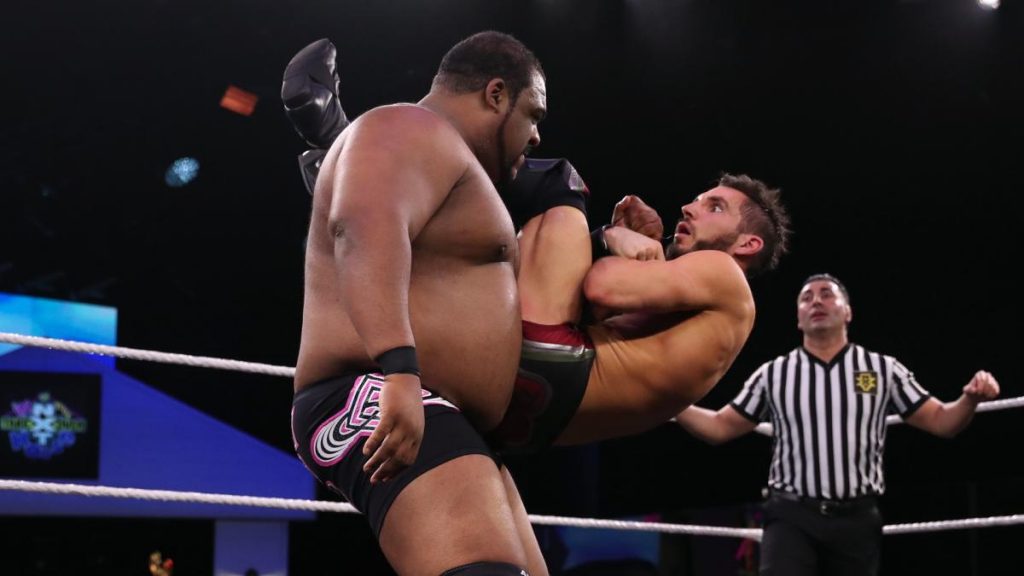 Keith Lee holds Johnny Gargano with one arm