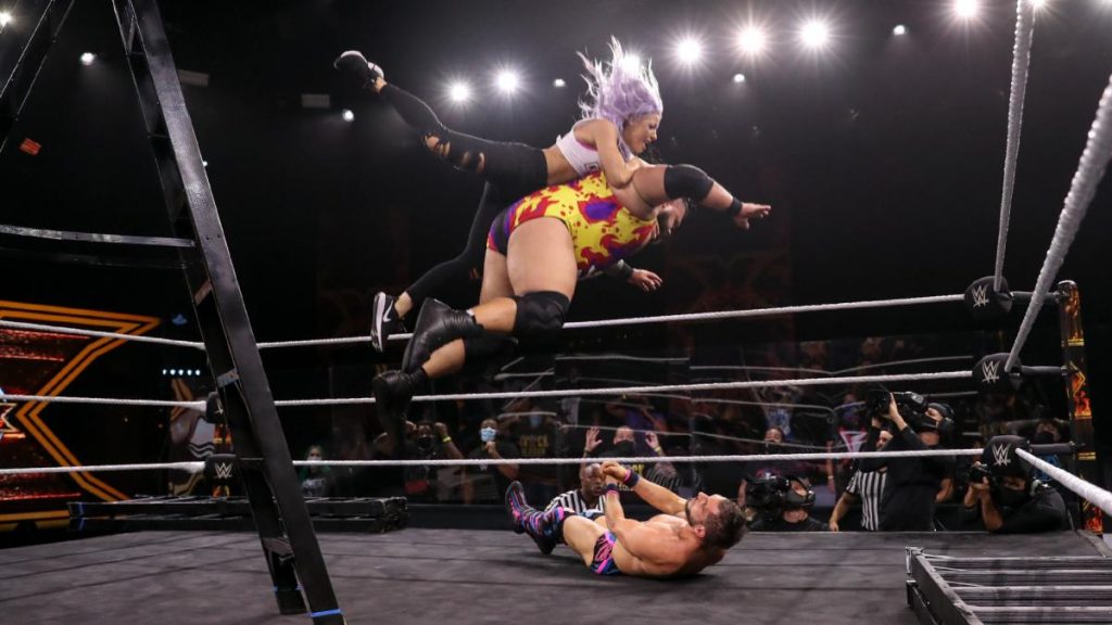 Bronson Reed splashes Johnny Gargano with Candice LeRae on his back