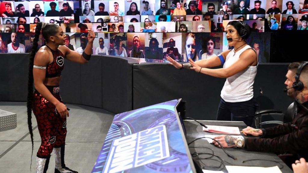 Bianca Belair and Bayley argue by the announce desk