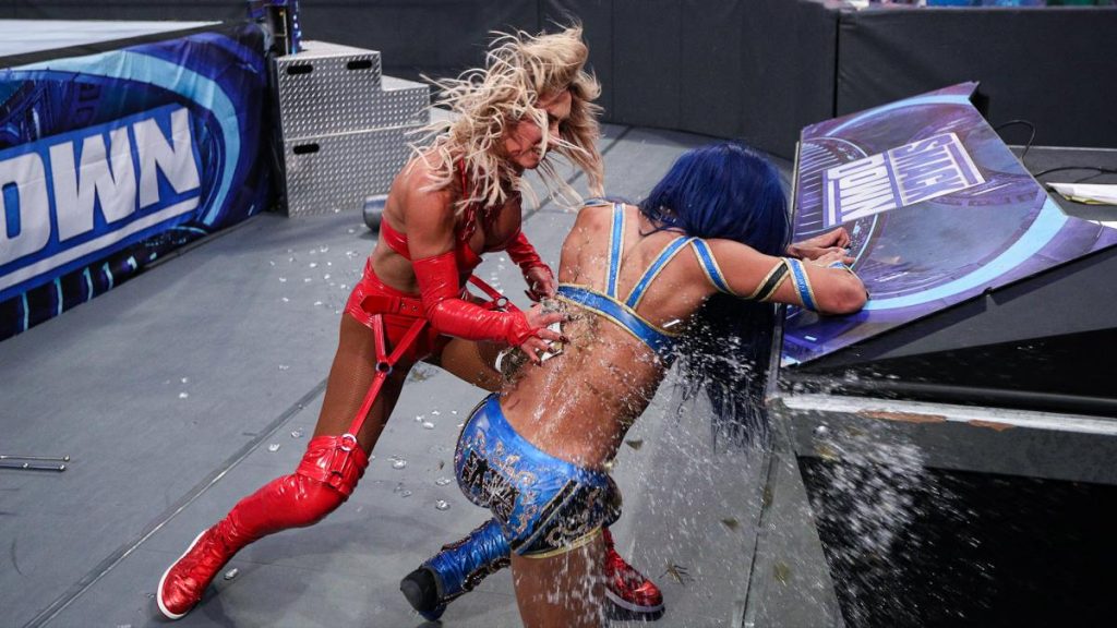 Carmella smashes a bottle of Sasha Banks' back