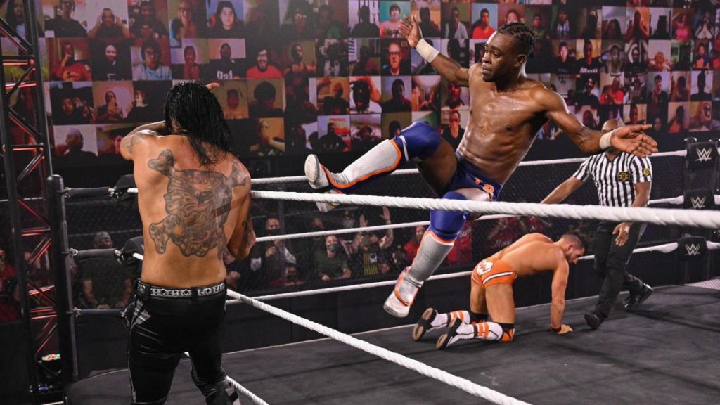 Leon Ruff dropkicks Damian Priest. Johnny Gargano in the background