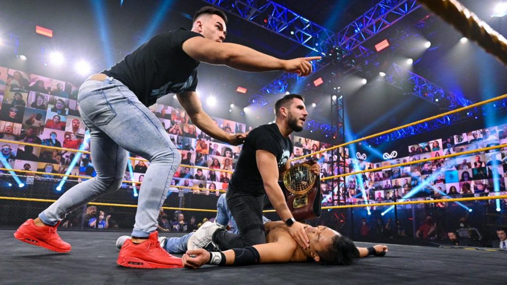 Austin Theory points out Dexter Lumis to Johnny Gargano as Gargano crouches over Kushida