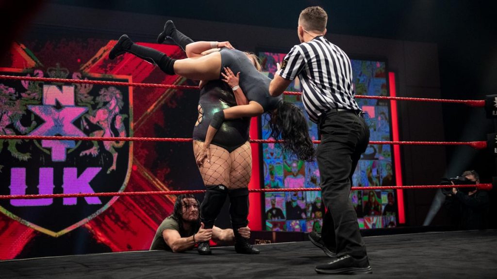 Joseph Connors reaches into the ring to grab Piper Niven's ankles