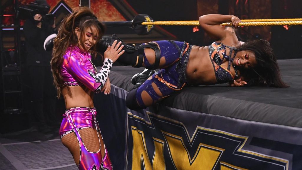 Ember Moon kicks Aliyah in the head while laying on the apron with Aliyah standing ringside