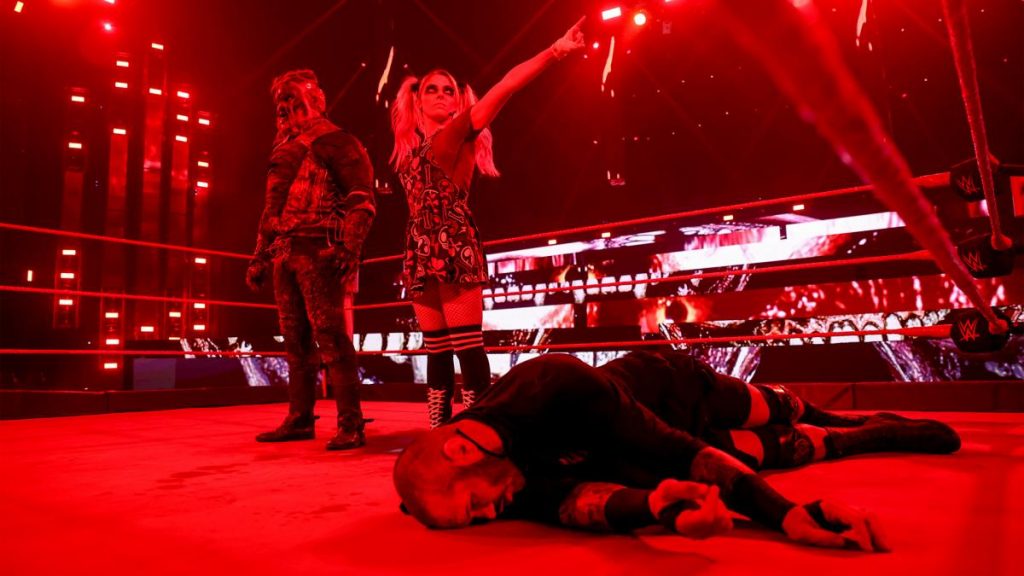 Alexa Bliss stands by the side of The Fiend and points at the WrestleMania sign, with Randy Orton laid out in front of them
