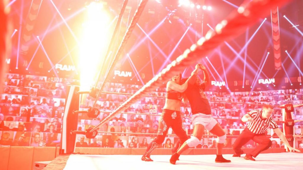 Fire shooting from the ringpost distracts Shayna Baszler from her Kirifuda Clutch on Reginald