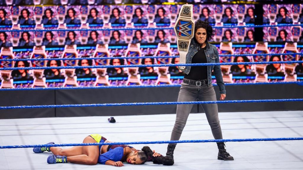 Bayley stands over Bianca Belair holding the title in a ThunderDome full of Bayleys