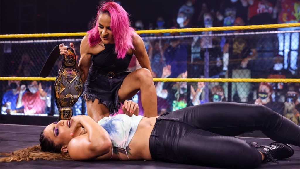 Dakota Kai kneels over Raquel Gonzalez