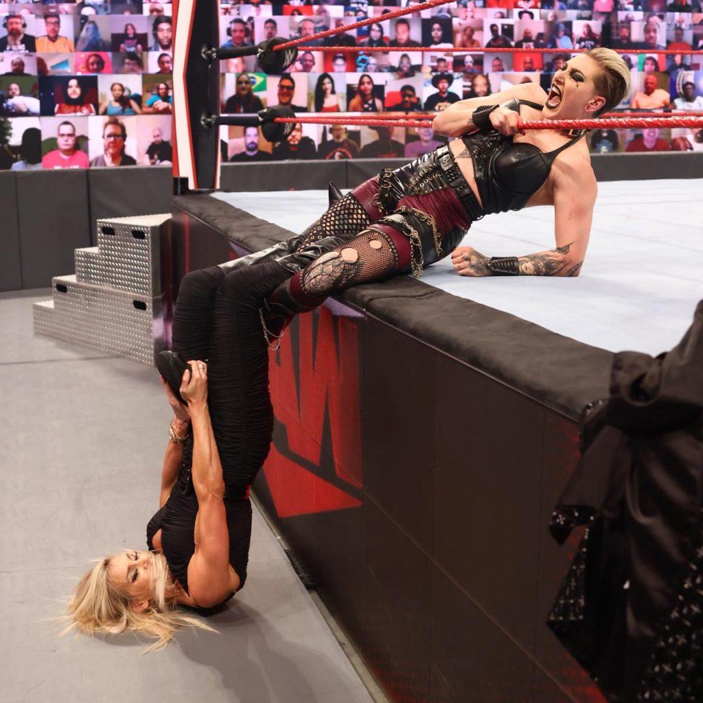 Charlotte Flair hangs off the edge of the ring with Rhea Ripley in a figure four