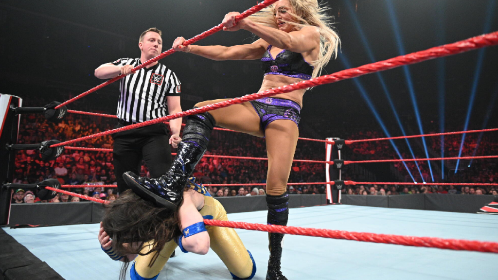 Charlotte Flair steps on Nikki A.S.H.'s neck on the ropes