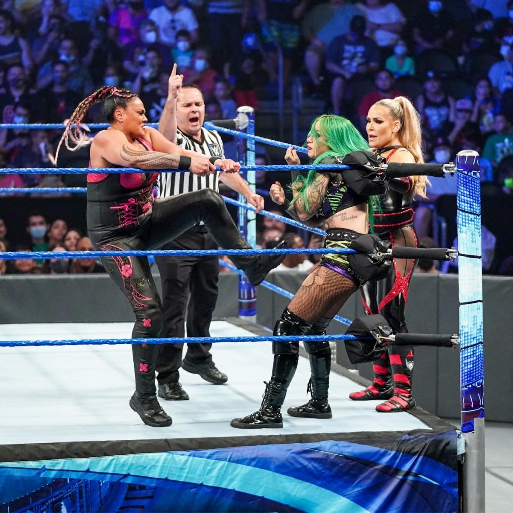 Tamina kicks Shotzi Blackheart in the corner while Natalya looks on