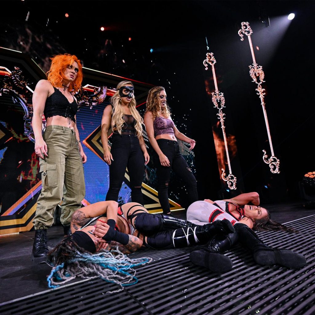 Gigi Dolan, Mandy Rose, and Jacy Jayne stand over Kayden Carter and Kacy Catanzaro