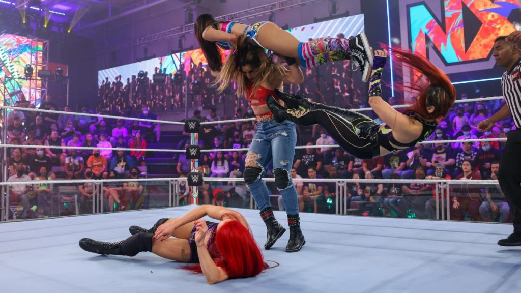Io Shirai kicks Cora Jade of Raquel Gonzalez' shoulders while she's trying to drop her on Kay Lee Ray