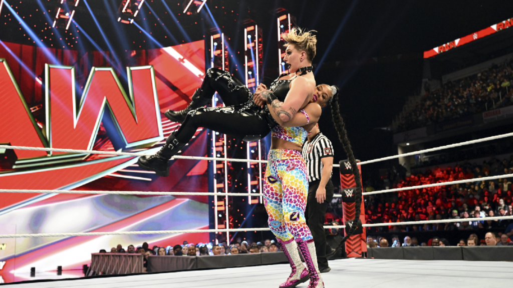 Bianca Belair with Rhea Ripley in the air ready to slam.