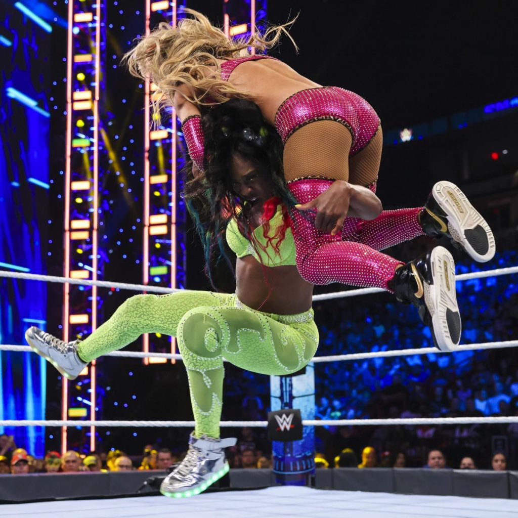 Naomi with Carmella on her shoulders in mid-air